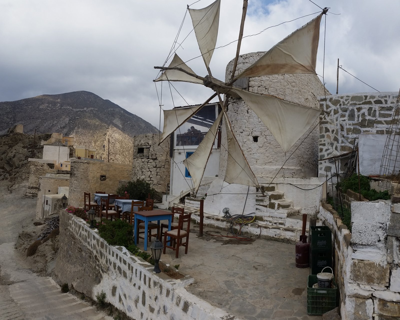 Sagoma di un mulino a vento in pietra sopra una baia di Karpathos al tramonto